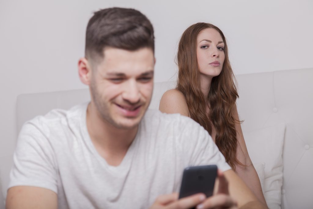 man looking at phone with jealous girlfriend