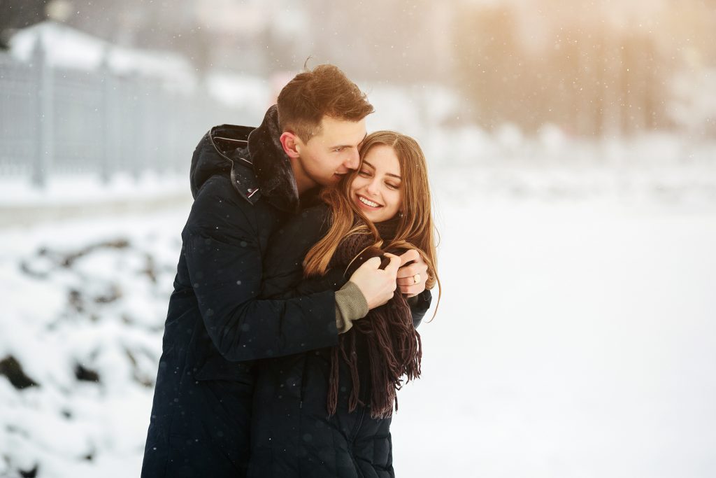 man hugging girlfriend in the snow