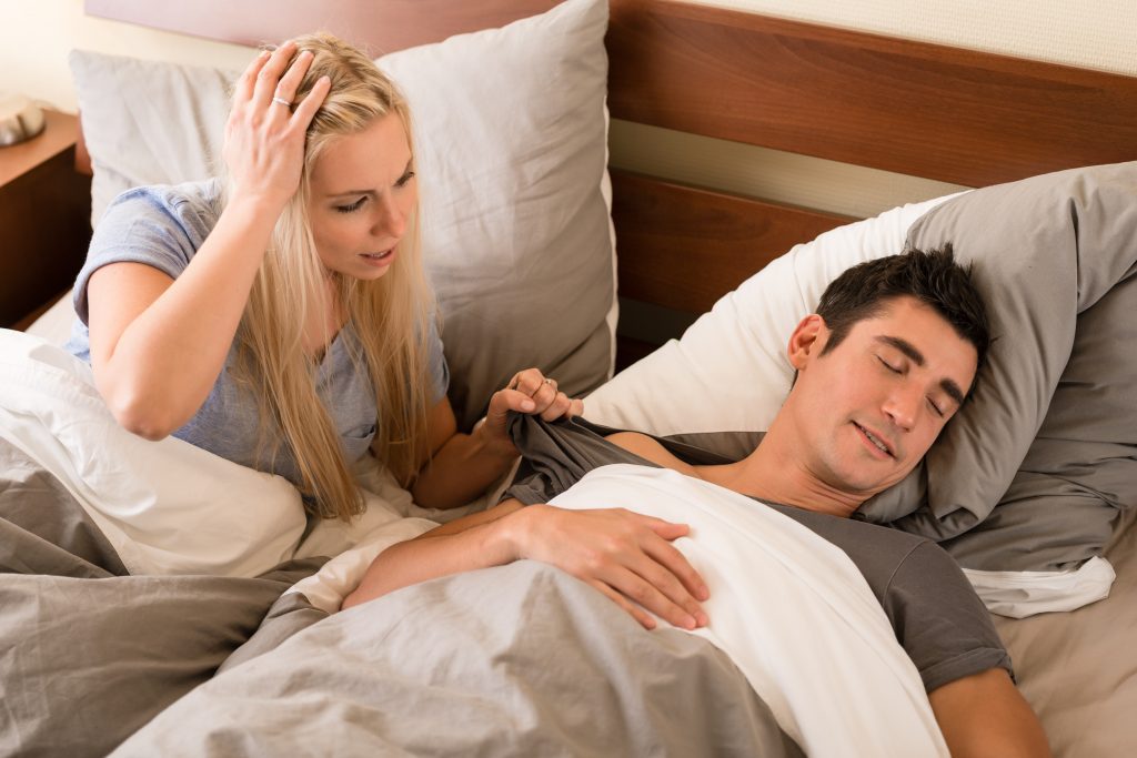 woman trying to talk to her sleeping boyfriend