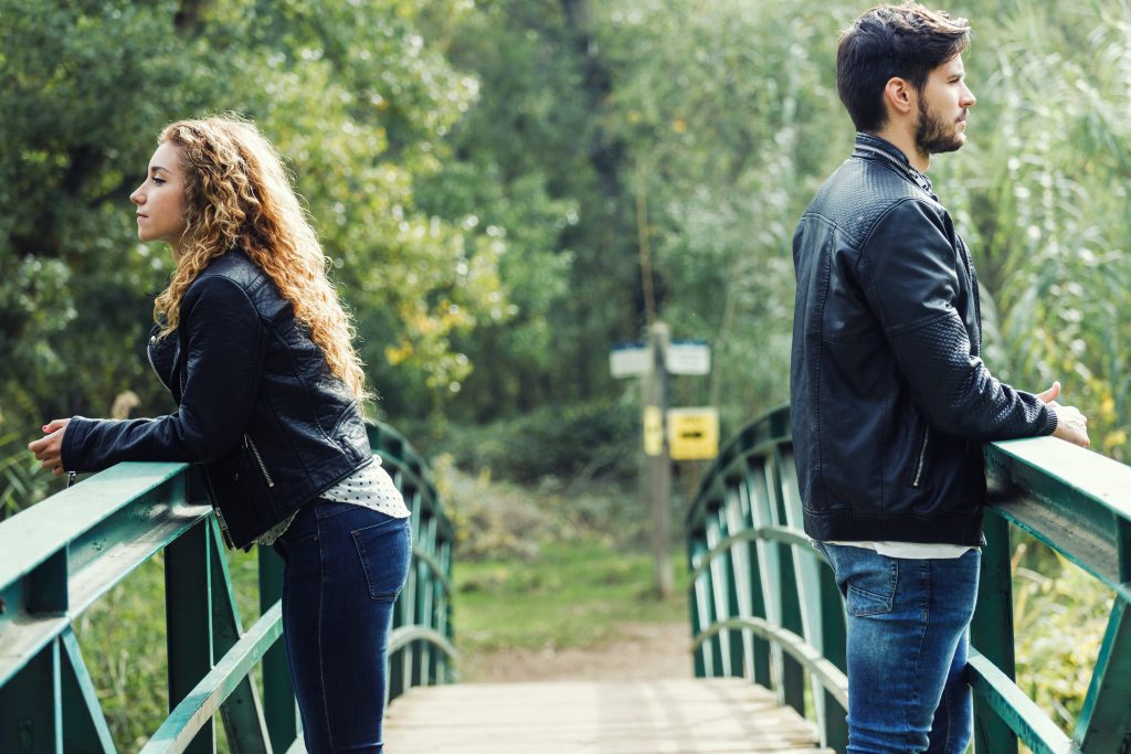 couple standing on bridge looking away from each other