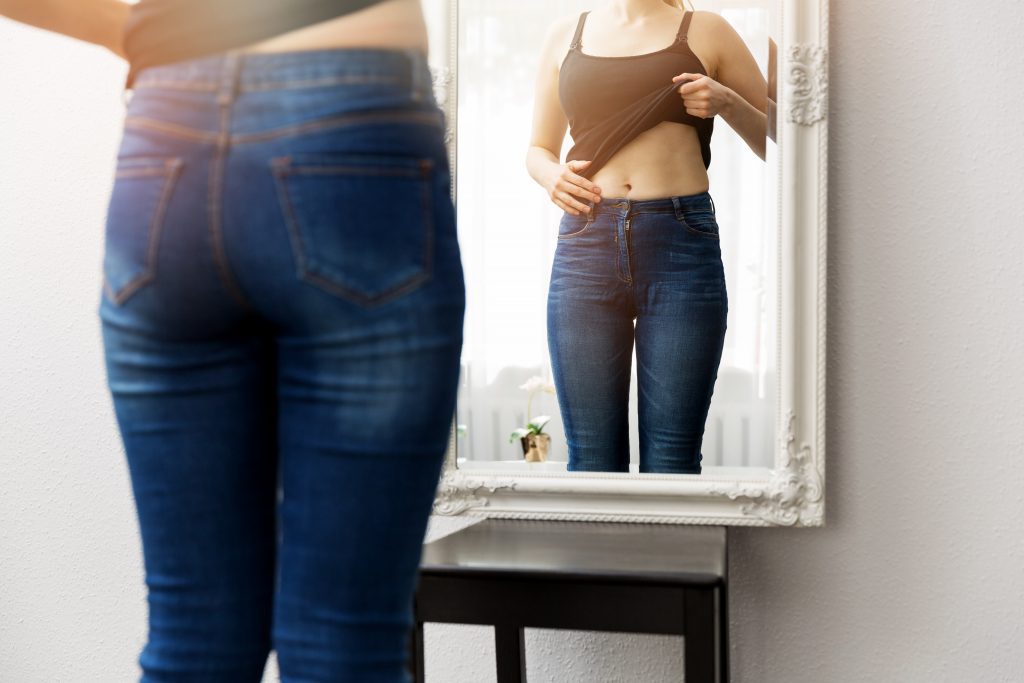 woman checking her body in the mirror