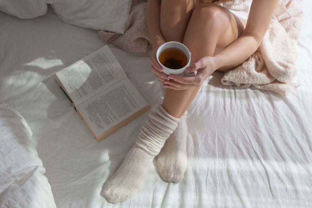 woman in bed with coffee and book
